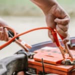 meccanico tenta di ricaricare una batteria dell'automobile con dei cavetti